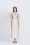 Woman wearing a long, elegant dress with sheer sleeves on a white background