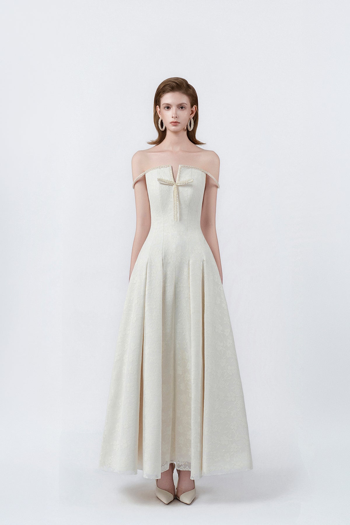 model in a cream off-the-shoulder flared maxi dress, DeTHEIA