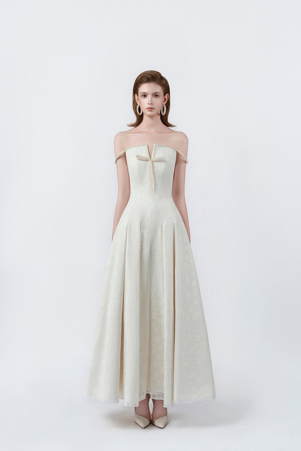 model in a cream off-the-shoulder flared maxi dress, DeTHEIA