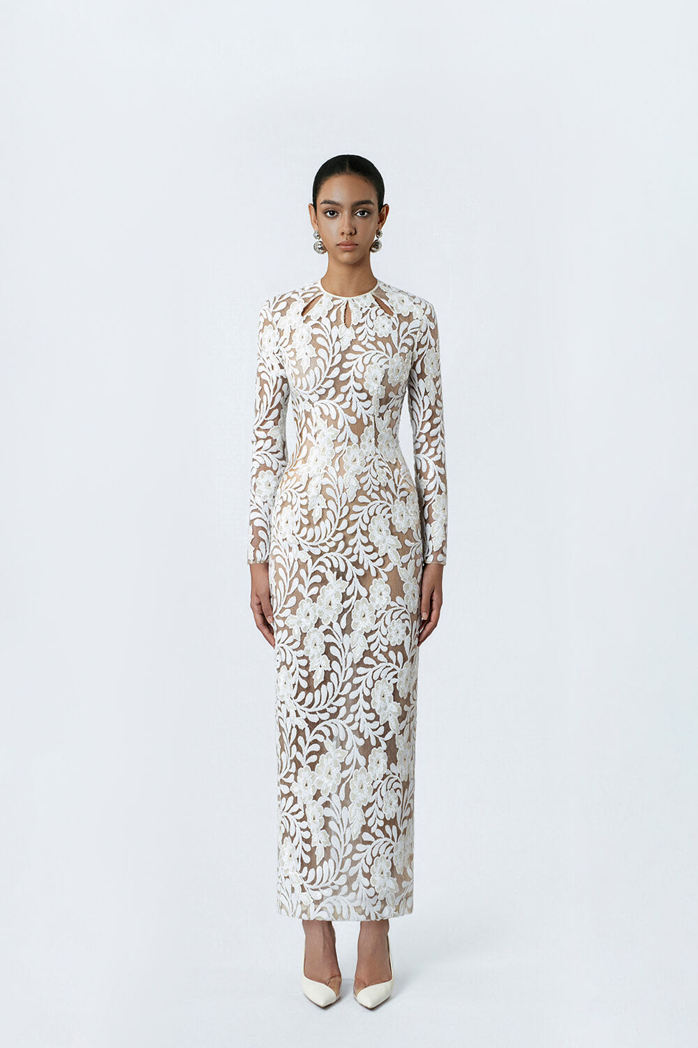 Woman wearing a long-sleeve, patterned dress on a white background