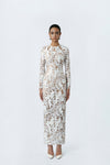 Woman wearing a long-sleeve, patterned dress on a white background