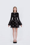 Black dress with pink bow pattern worn by a model on a white background